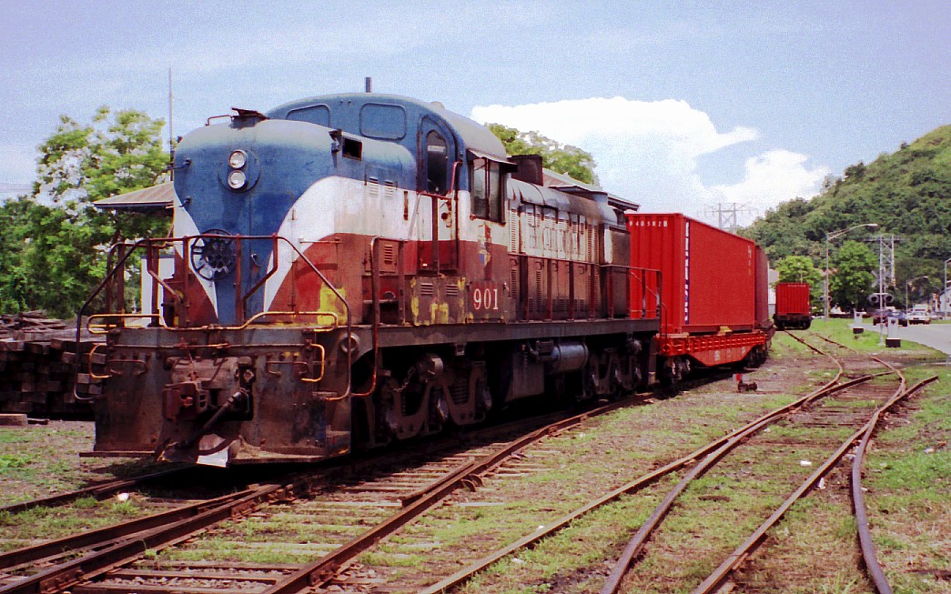 a red, blue, and white train pulling cargo cars