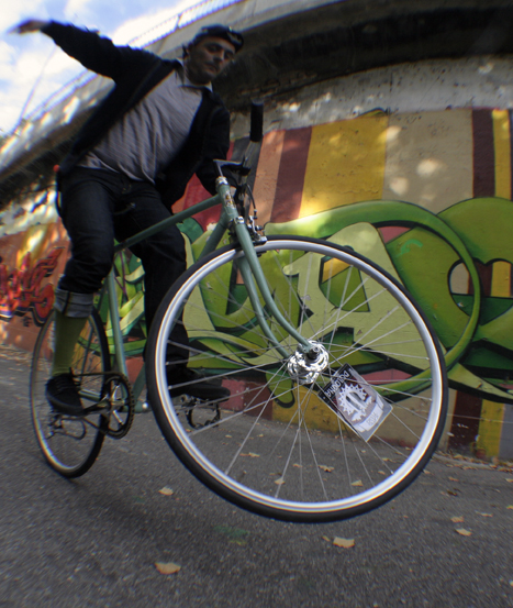 a bicyclist performing an inverted trick in front of graffiti