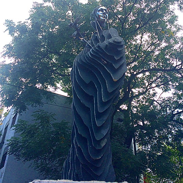 a tall statue is surrounded by trees