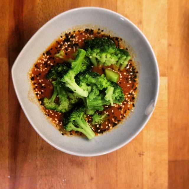 a bowl of broccoli and red sauce on a wooden table