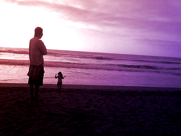 a man on the beach standing next to a dog