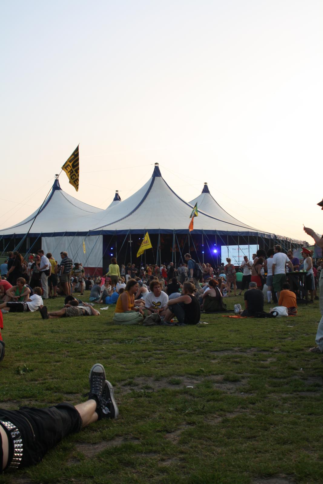 a couple of people are sitting in the grass under tents