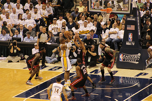 some basketball players playing a game with spectators in the stands
