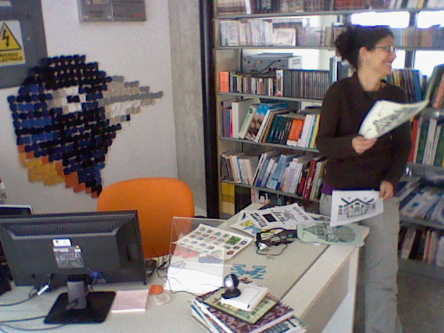 a woman in glasses standing next to a book shelf