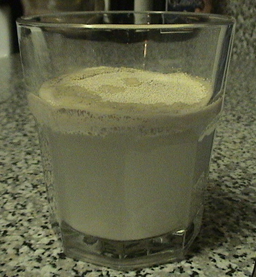 a glass filled with white liquid sitting on top of a counter