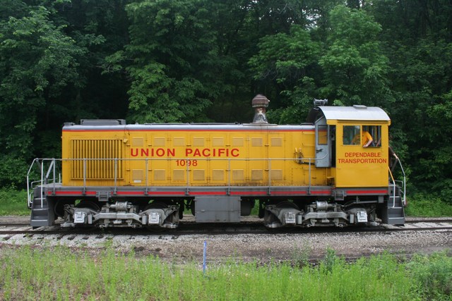 a yellow train traveling on train tracks near trees