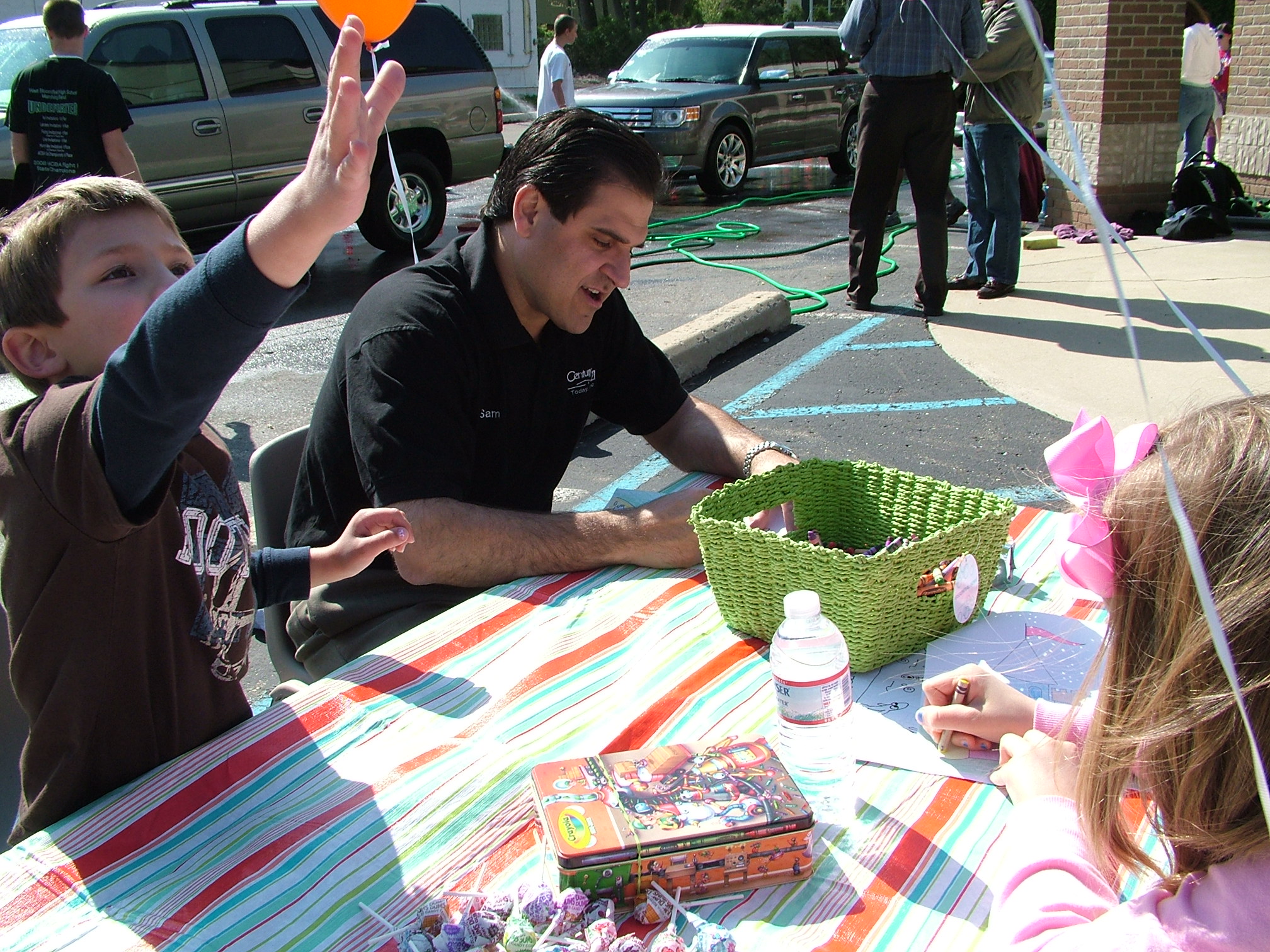 a man and two children sit at a table at an outdoor event