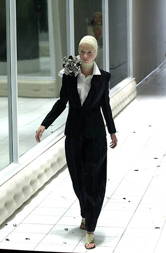woman in black suit walking with metal mask on head