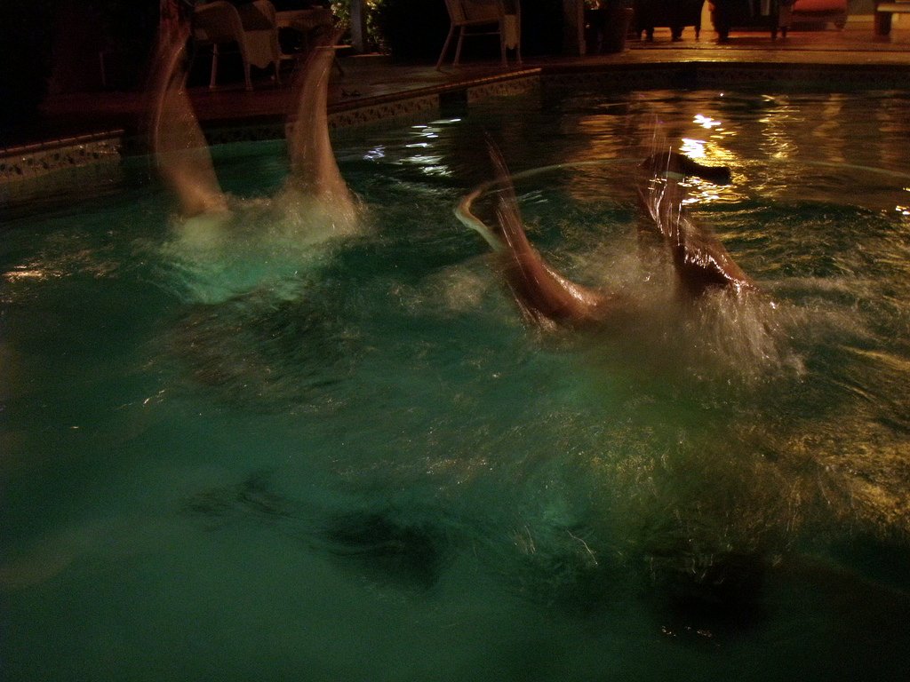 three people are in a pool while one person lifts his feet up