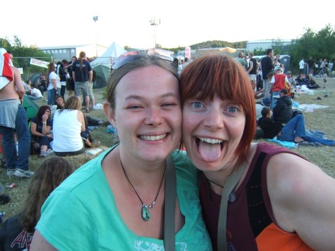 two women stand at a music festival in front of a crowd