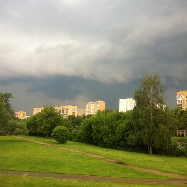 a stormy sky above a park area with a lush green field