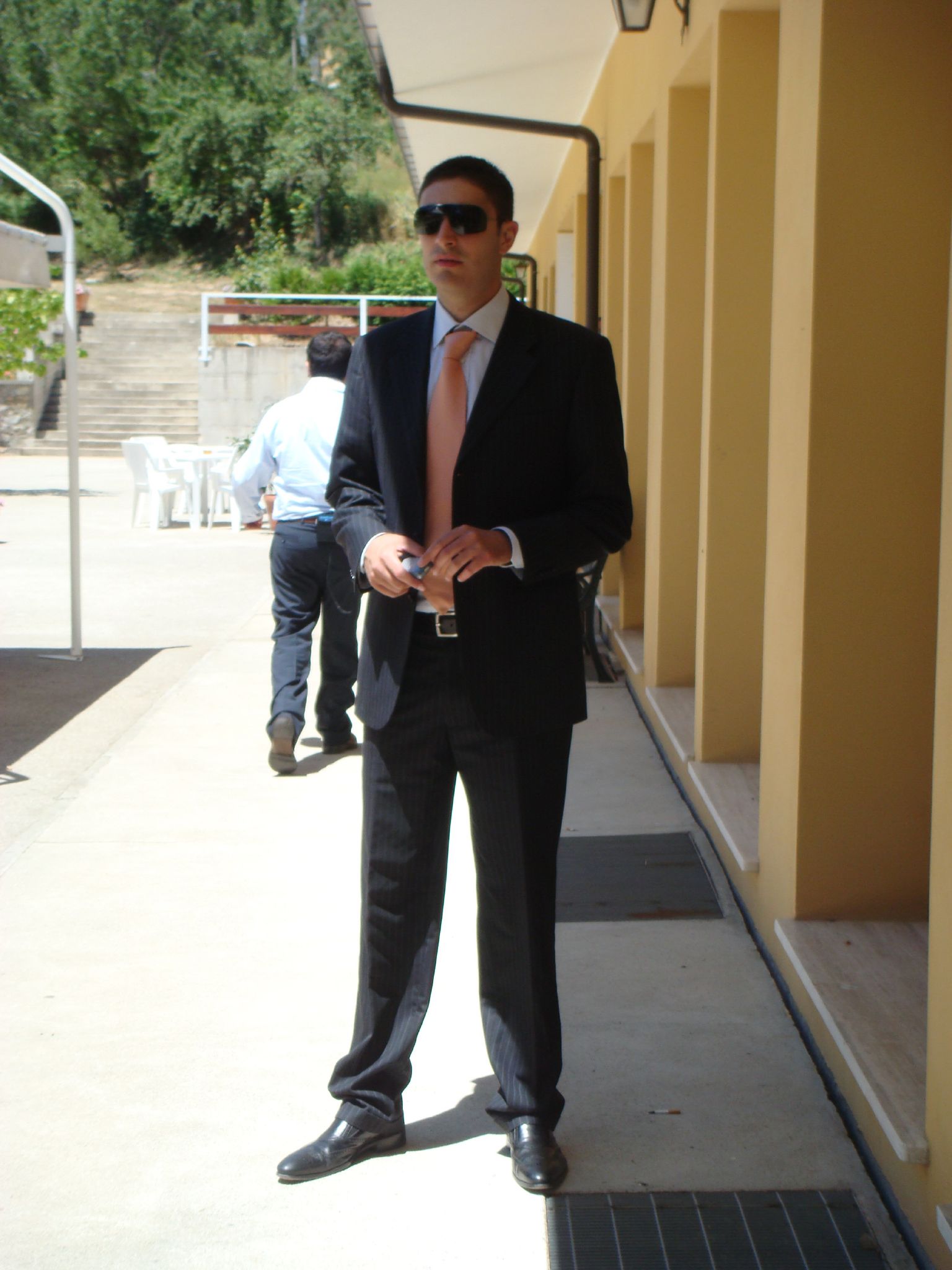 a man in a suit and tie stands outside on the side walk