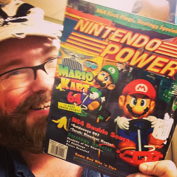 a man looking up and holding up the cover of nintendo power
