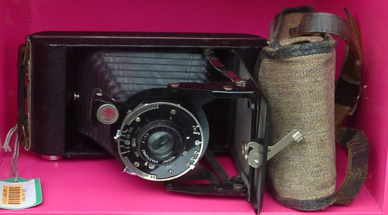 a old fashioned camera is sitting in a pink box