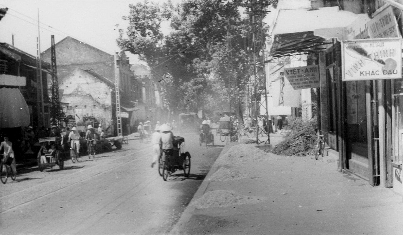 antique black and white po of people on motorcycles riding down a street