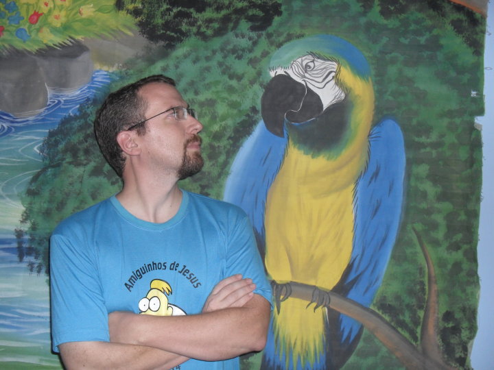 a man standing next to a painted parrot