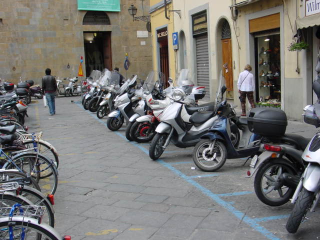 many motorcycles are parked along the sidewalk outside the building