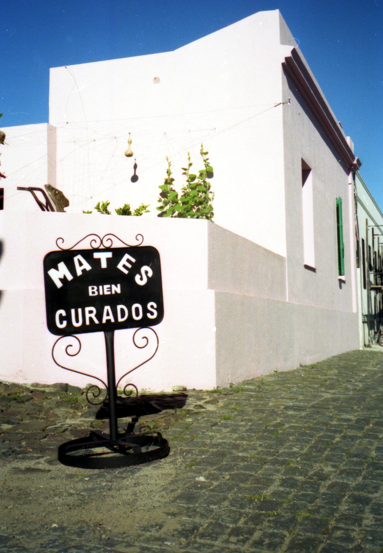 a black sign is by a building and cobblestone area