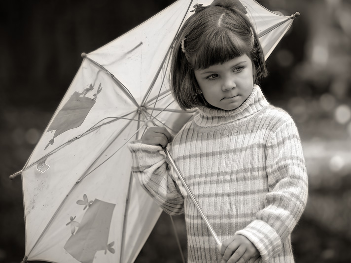 a small girl holds onto an open umbrella