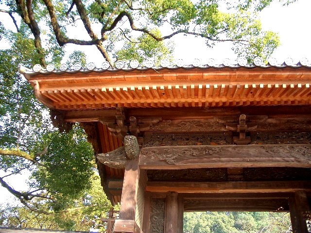a tall asian building with a wooden roof and a bell on it