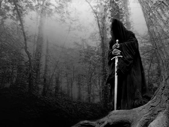 the man in a cloak holding a sword standing in a forest