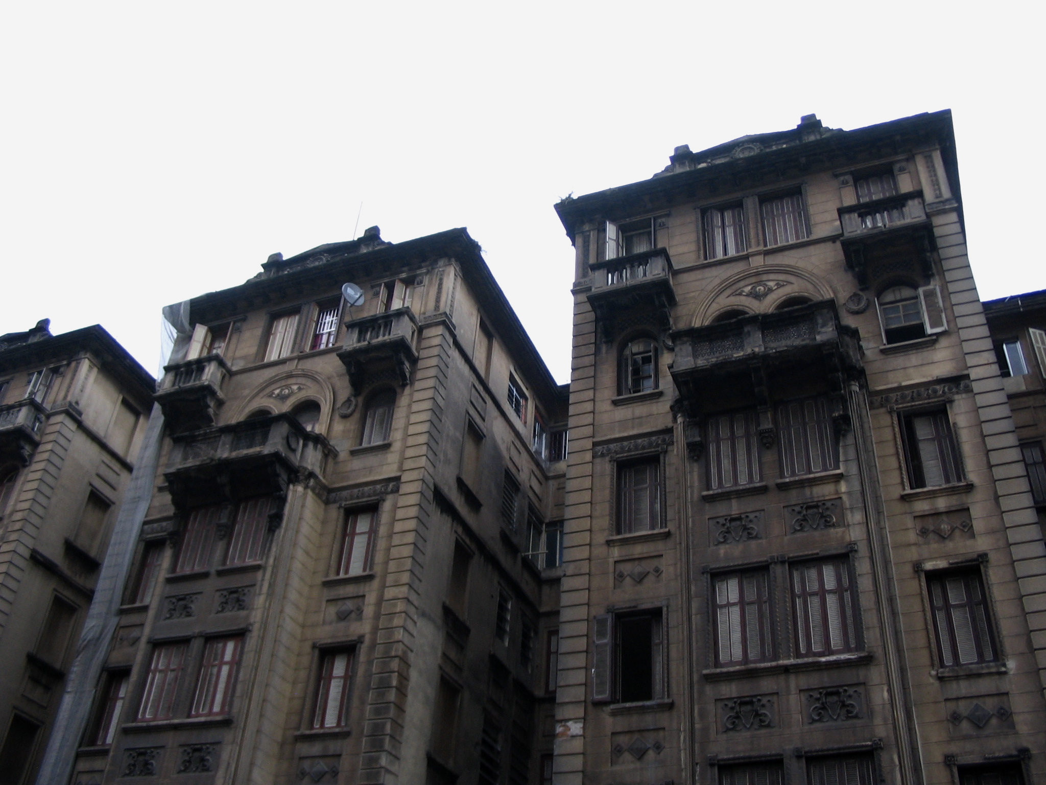 three tall buildings on an overcast day with one of them has clocks on each window