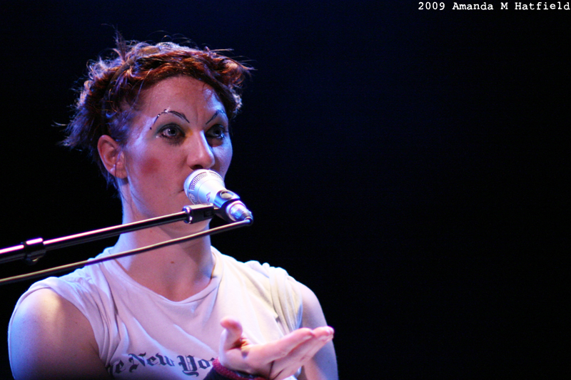 woman with piercings and short hair singing into microphone