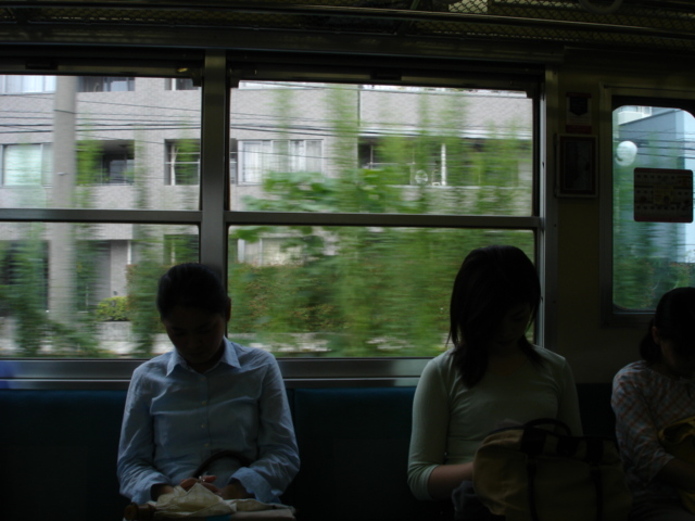 three people sitting on a train car looking out the window