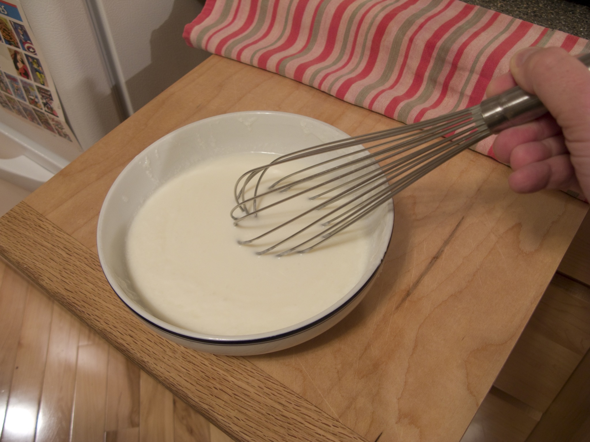 a hand mixing some white batter into a bowl