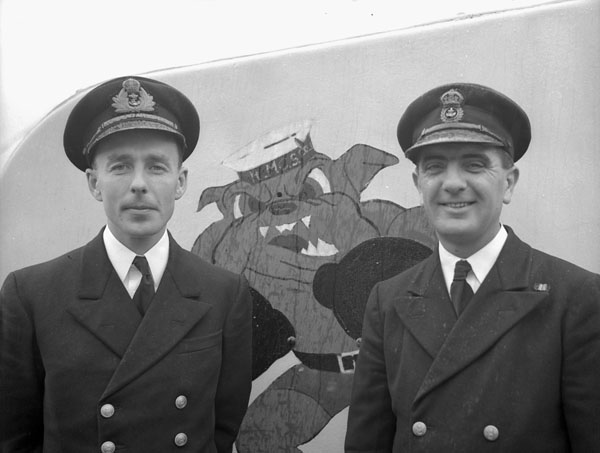 two men in uniform stand next to a bear painting