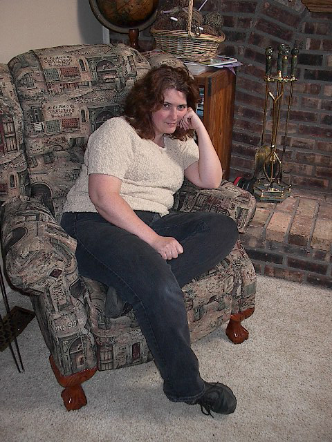 a woman sitting in a chair in front of a fireplace