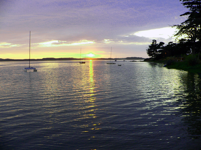 some sail boats floating on water at dusk