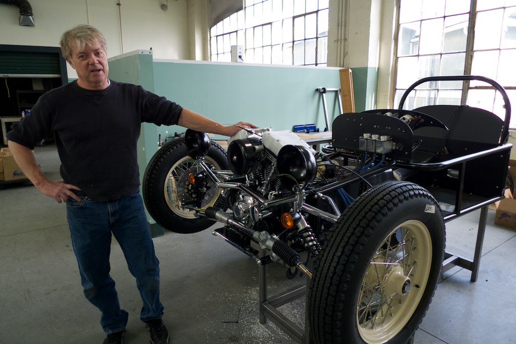 a man posing with an engine in a shop