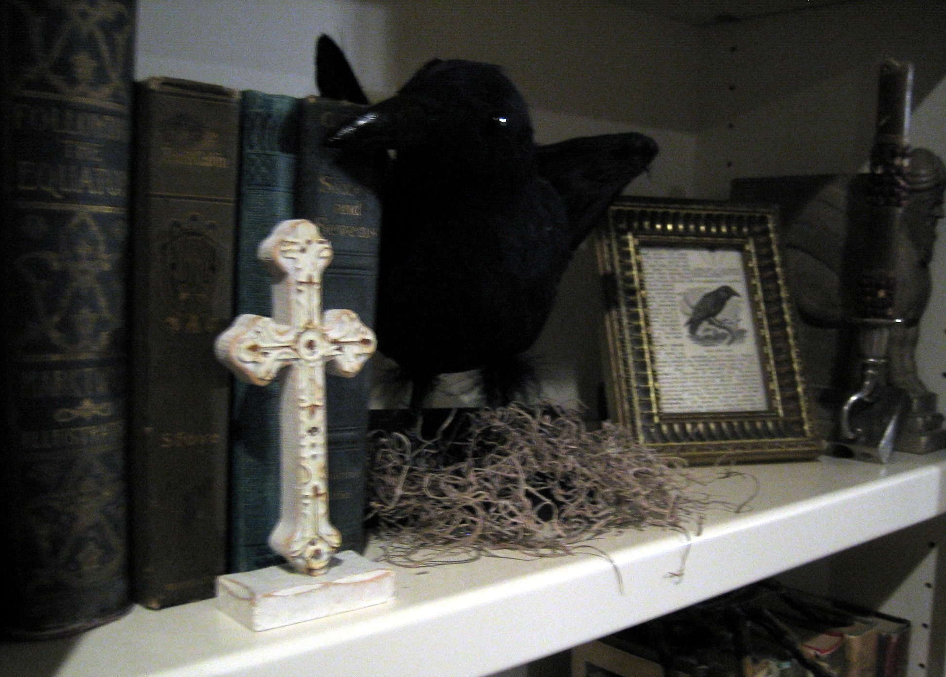 a white shelf topped with books and a cross