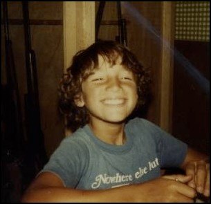 a boy smiles while sitting in front of a mirror