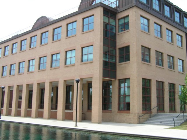 a brown building has a long pool of water in front