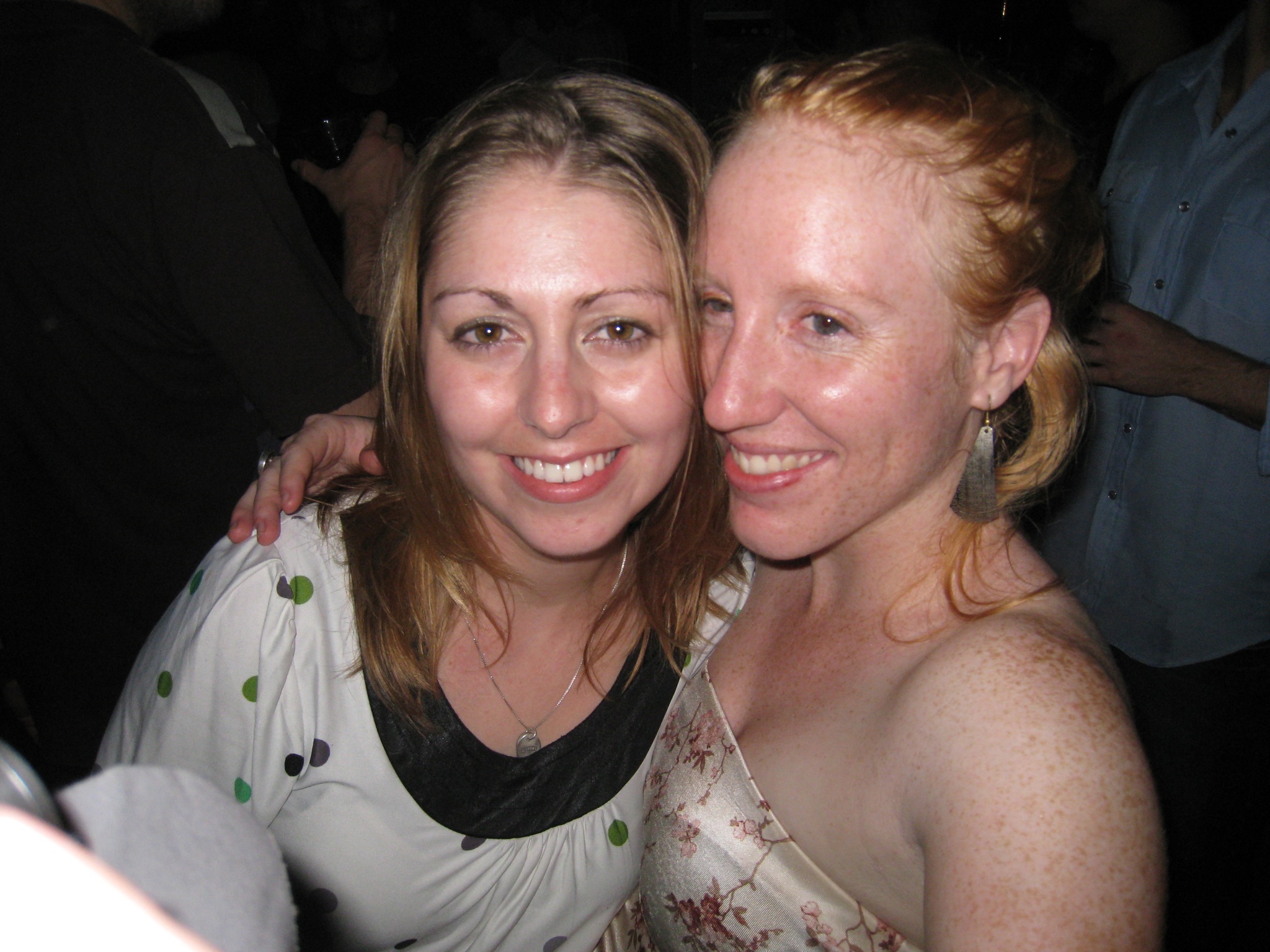 two women standing next to each other in a dark room