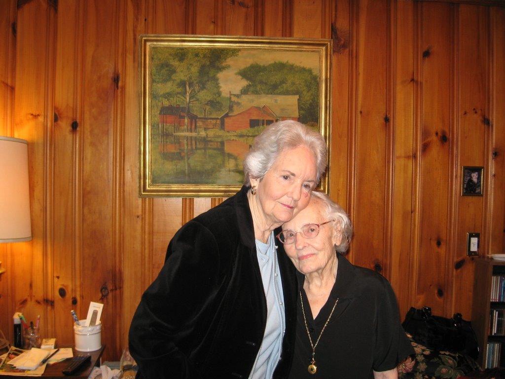 two older ladies in front of a wooden wall