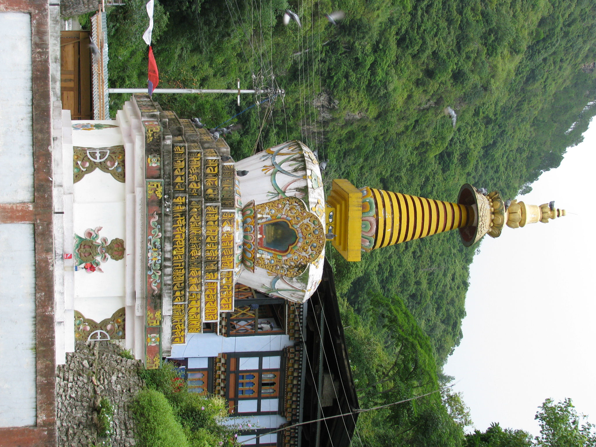 a tall golden and white structure with several levels next to a mountain