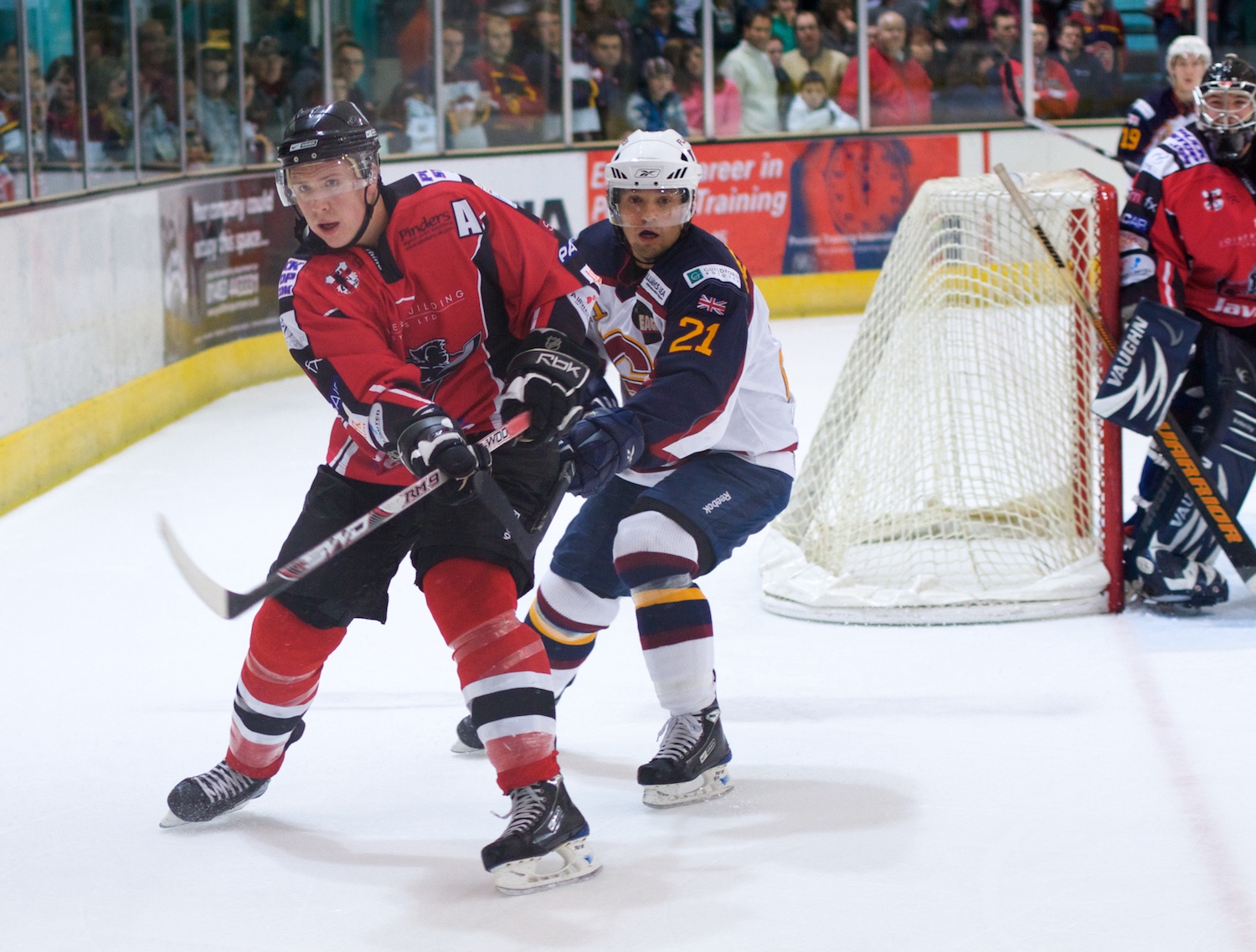 two young men in red and black uniforms on ice