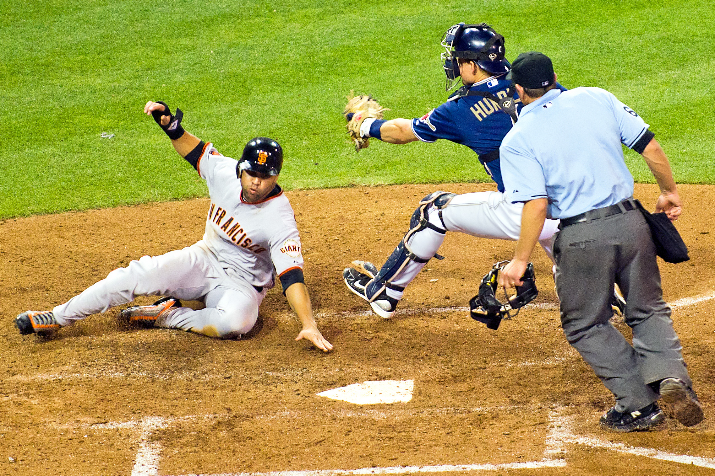 a baseball player sliding into home plate and being tagged by the umpire