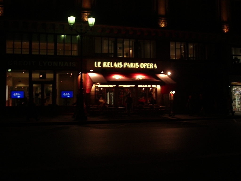 people standing outside a cafe at night in the dark