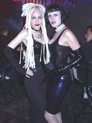 two women posing for the camera while dressed up