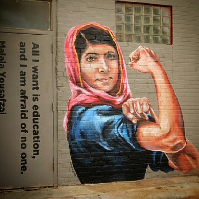 the street is covered with graffiti and features a woman in a scarf