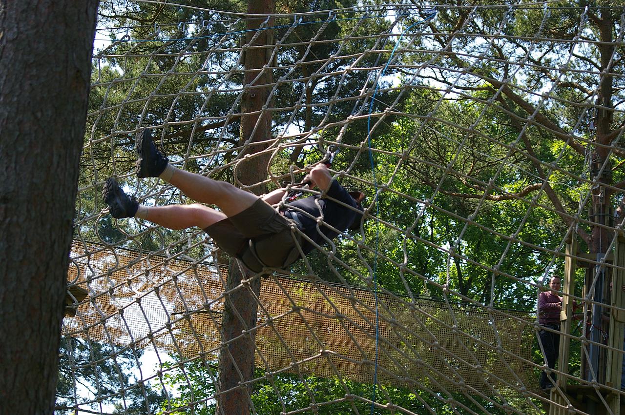 a person hangs on a rope course in the woods