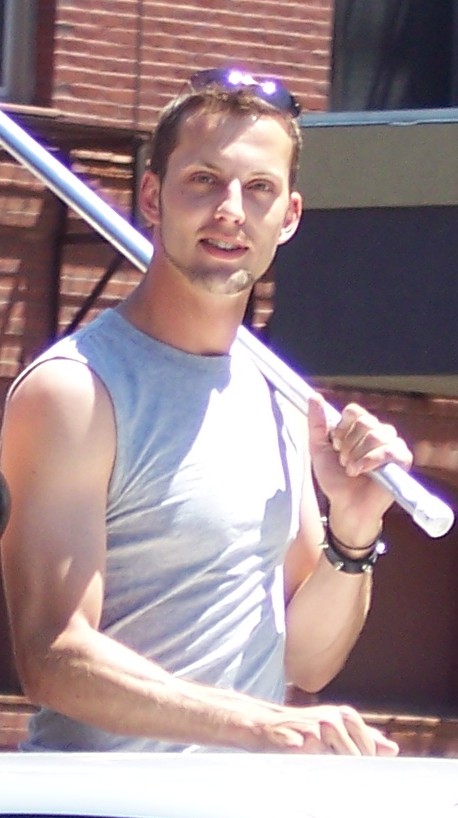 a young man holding a baseball bat on the side of a road