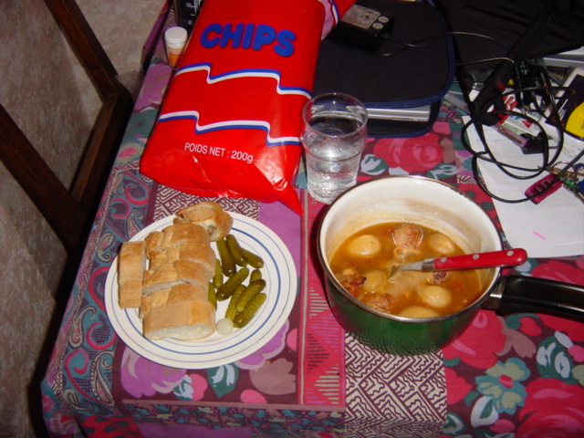 a red towel sits on top of the table, with a bowl of soup and a container of chips