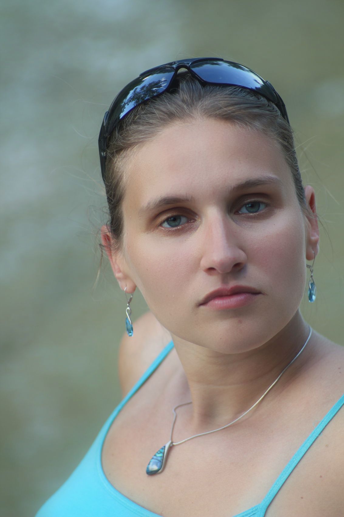 a woman in a blue top and silver earrings