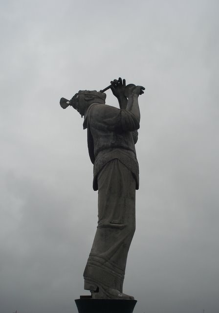 a tall statue of a lady holding a violin near the sky