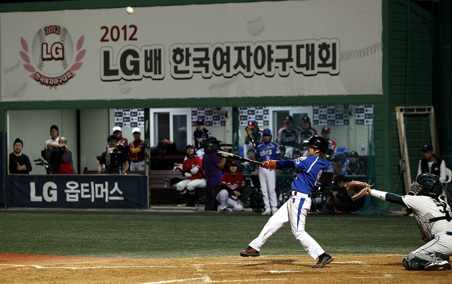 baseball player taking swing at a baseball during a game